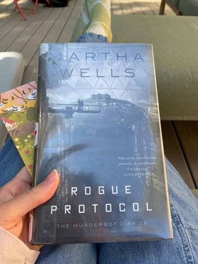 Rogue Protocol Hand holding Rogue Protocol book by Martha Wells.