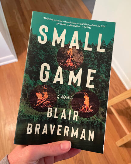 Small Game Hand holding up Small Game book by Blair Braverman.